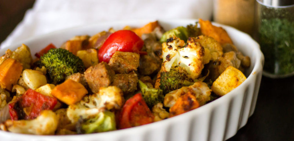 a sheet pan meal with tomatoes, broccoli, cauliflower, sweet potatoes, and beef